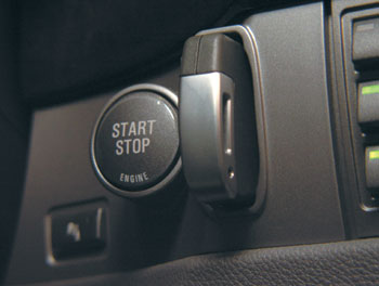 Для запуска двигателя необходимо разместить электронный ключ в особой прорези, а затем нажать вот эту кнопку. Система, позволяющая попадать внутрь и запускать двигатель без всяких операций с ключом, отнесена к опциям.