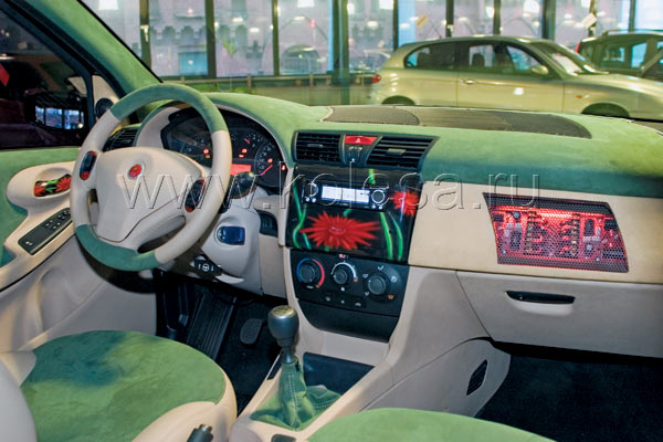 Вместо невзрачного пластика - светлая кожа и зеленая алькантра. И масса приятных мелочей. За черной решеткой над "бардачком" - освещенное красным светом "гнездо" пассивных фильтров DLS